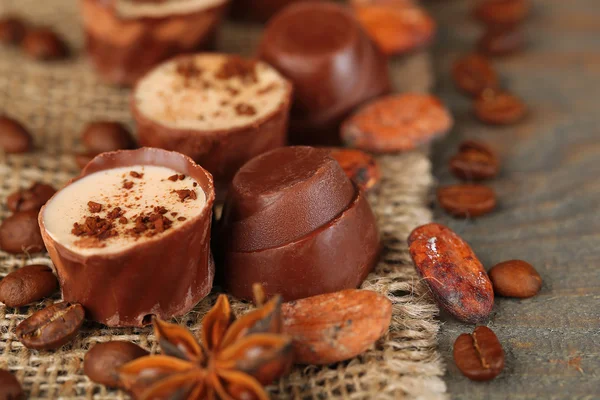 Вкусные шоколадные конфеты с кофейными зернами и орехами на деревянном фоне — стоковое фото