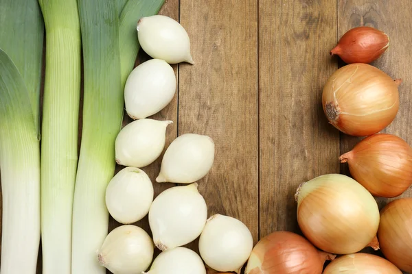 Different raw onion on wooden background — Stock Photo, Image