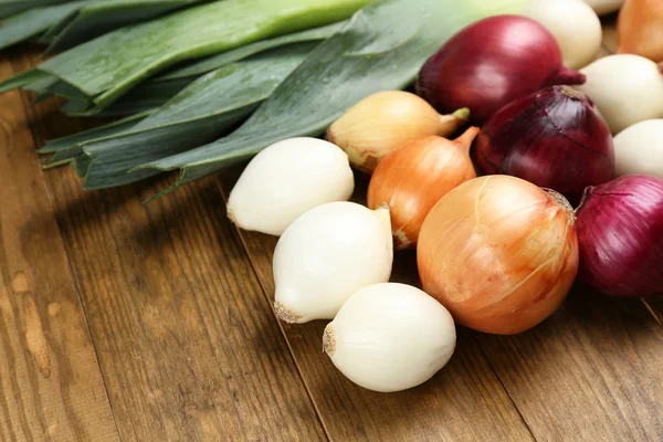 Different raw onion on wooden background — Stock Photo, Image