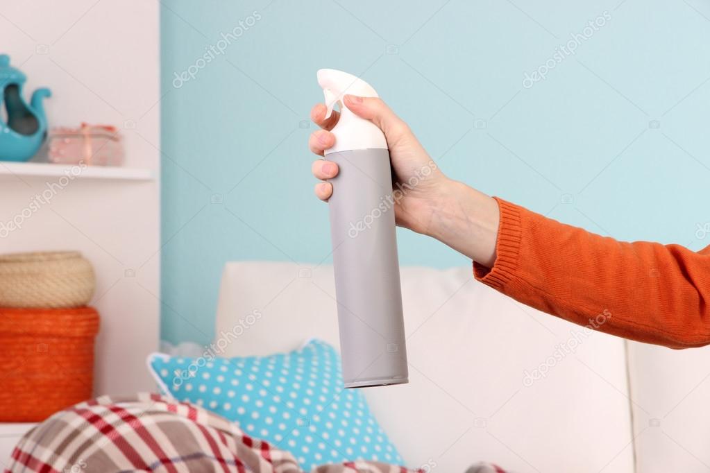 Sprayed air freshener in hand on home interior background Stock Photo