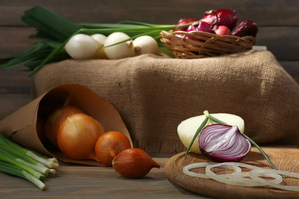 Different raw onion on wooden background — Stock Photo, Image