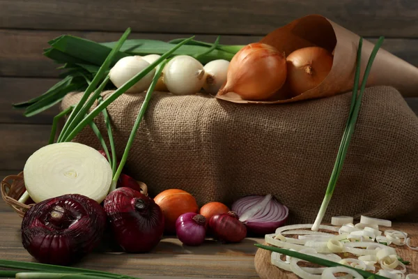 Verschiedene rohe Zwiebeln auf Holzgrund — Stockfoto