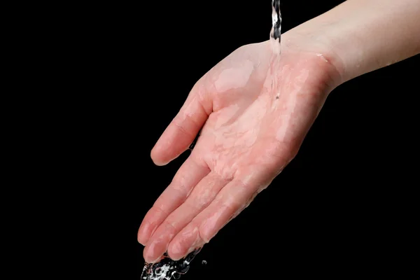 Menschliche Hand mit Wasser, das auf sie spritzt, auf schwarzem Hintergrund — Stockfoto