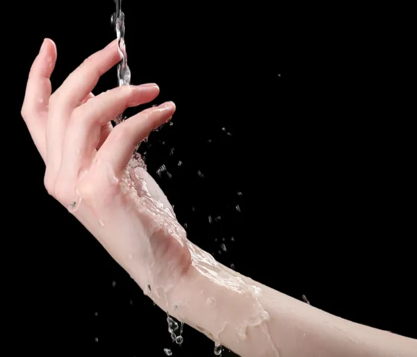 Emberi kéz a vizet fröcskölő őket a fekete háttér — Stock Fotó