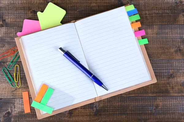 Cuaderno, bolígrafo y pegatinas sobre fondo de madera — Foto de Stock