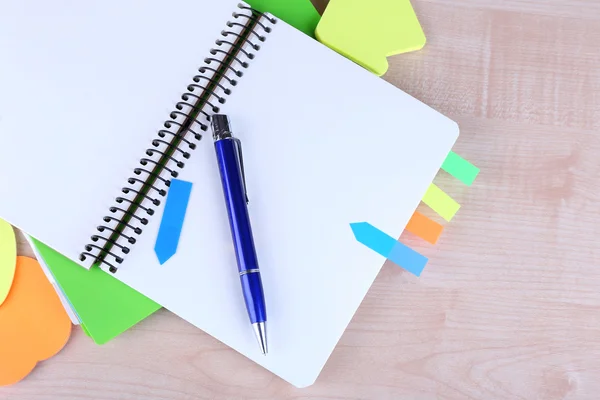 Cuaderno, bolígrafo y pegatinas sobre fondo de madera — Foto de Stock
