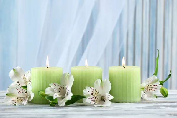 Beautiful candles with flowers on wooden table, on dark background — Stock Photo, Image