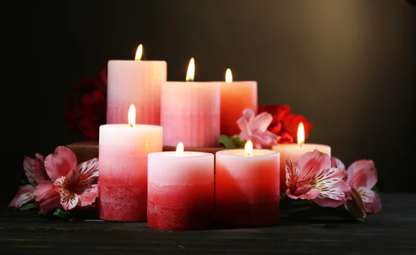 Belles bougies avec des fleurs sur table en bois, sur fond sombre — Photo