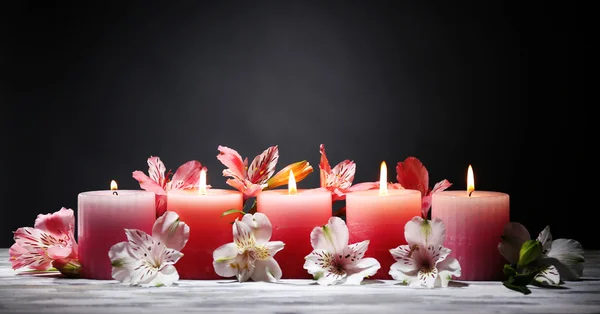美丽的蜡烛，上面放着木桌前，在深色背景上花 — 图库照片