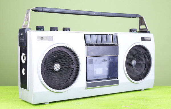 Retro cassette stereo recorder on table on green background