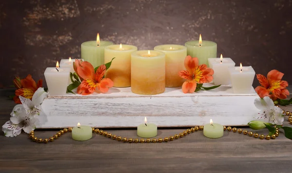 Schöne Kerzen mit Blumen auf dem Tisch auf braunem Hintergrund — Stockfoto