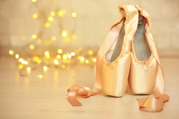 Ballet pointe shoes on floor on bokeh background — Stock Photo, Image