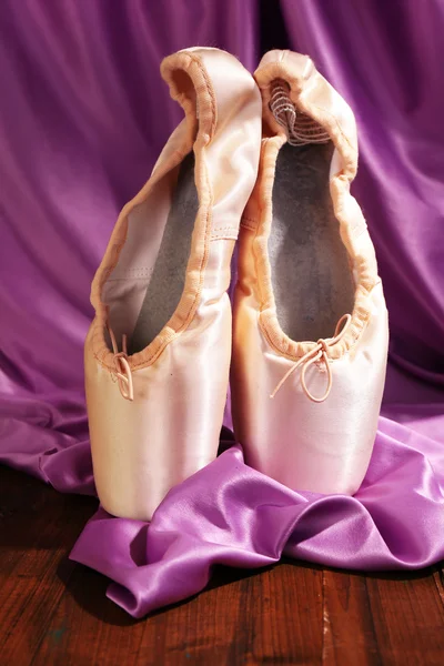 Sapatos de ponteiro de balé no chão de madeira no fundo do tecido — Fotografia de Stock