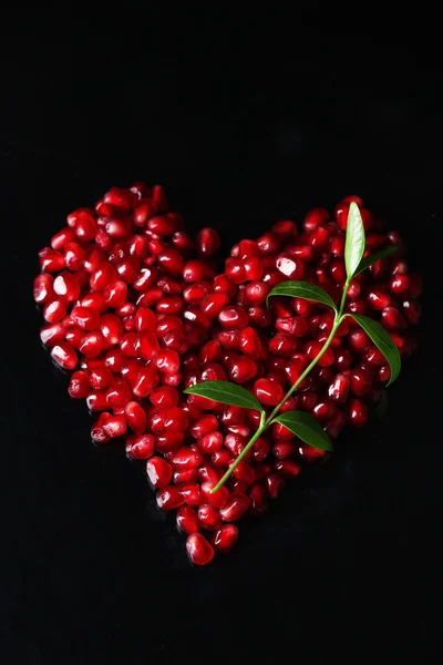 Heart made of seeds of pomegranate isolated on black — Stock Photo, Image