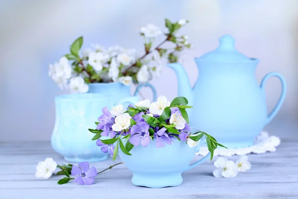 Beautiful spring flowers in cups on wooden table — Stock Photo, Image