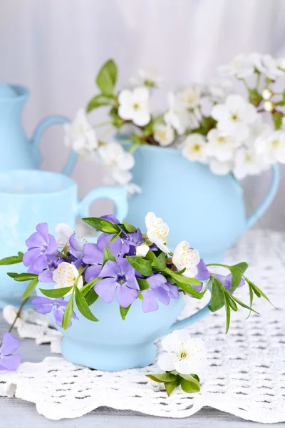 Vackra vårblommor i koppar på träbord — Stockfoto