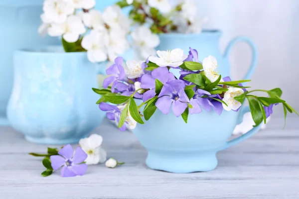 Krásný jarní květiny v cups na dřevěný stůl — Stock fotografie