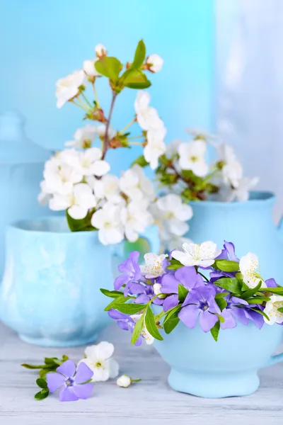 Vackra vårblommor i koppar på träbord — Stockfoto