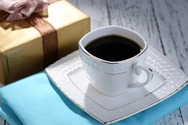 Tasse Kaffee und Geschenk auf Holztisch in Großaufnahme — Stockfoto