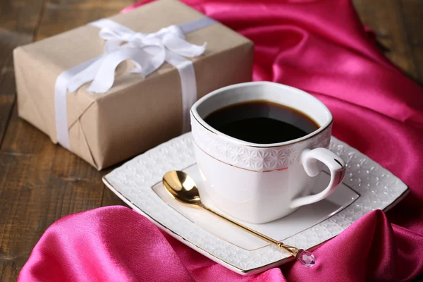 Tazza di caffè e regalo sul tavolo in legno primo piano — Foto Stock