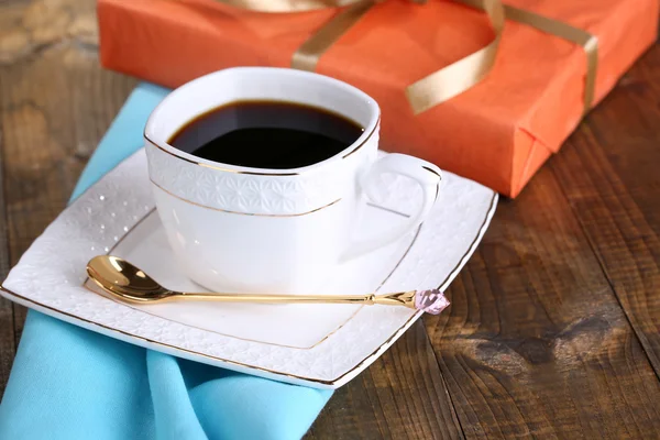 Cup of coffee and gift on wooden table close-up — Stock Photo, Image