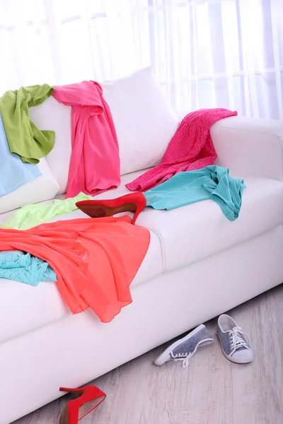 Messy colorful clothing on  sofa on light background — Stock Photo, Image