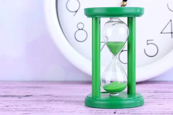 Hourglass and big clock on light background — Stock Photo, Image