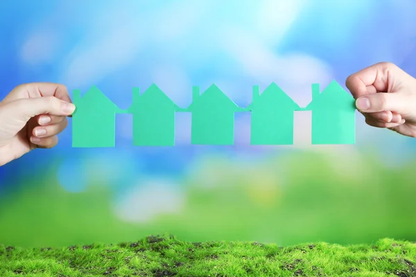 Hands hold houses on grass on natural background Stock Image
