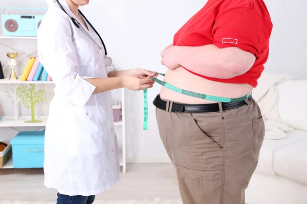 Médecin examinant l'obésité du patient sur fond de lumière Image En Vente