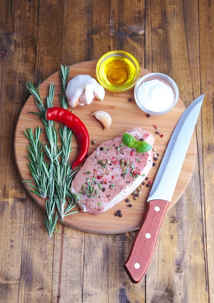 Raw meat steak with herbs and spices on cutting board, on wooden background — Stock Photo, Image
