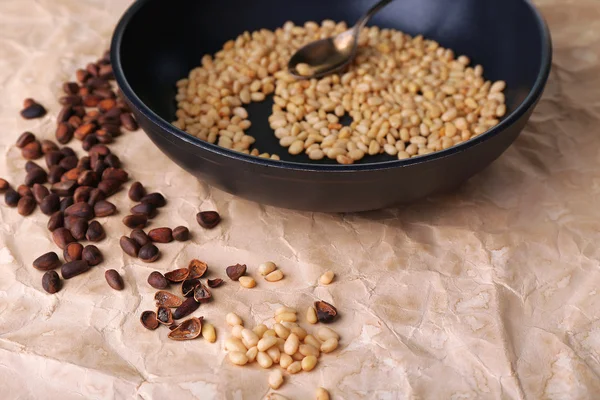 Cedar pine nuts on pan, on wooden table — Stock Photo, Image