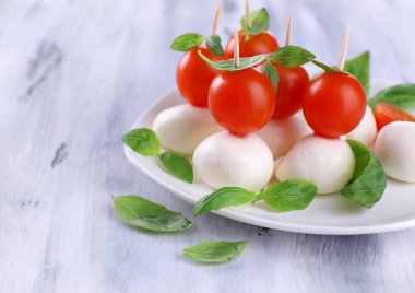 ahşap masa tabakta domates ve fesleğen ile lezzetli mozzarella peyniri