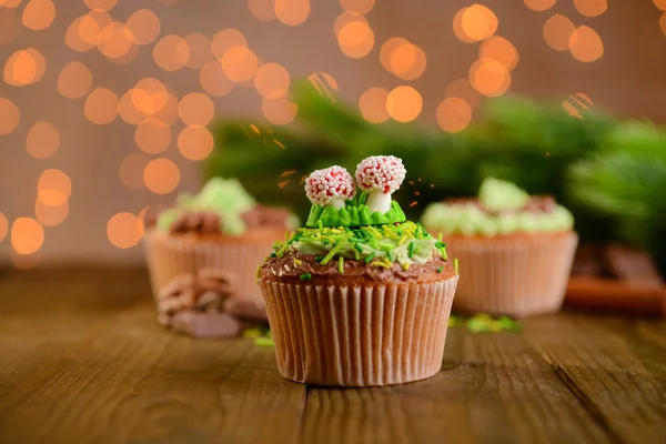 Cupcakes saborosos com creme de manteiga, na mesa de madeira, no fundo brilhante — Fotografia de Stock