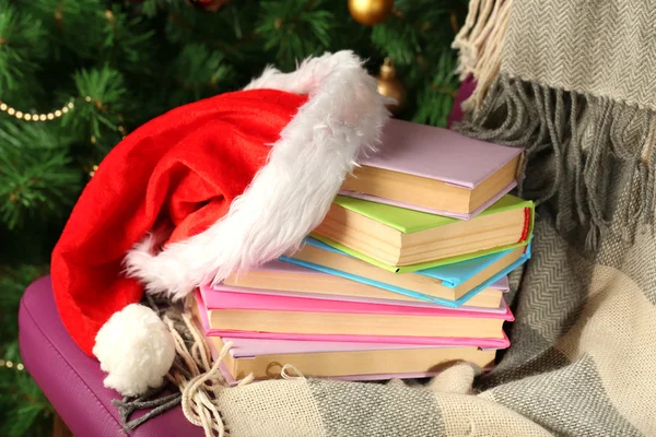 Composición con libros y cuadros, sombrero rojo, en silla sobre fondo de árbol de Navidad — Foto de Stock