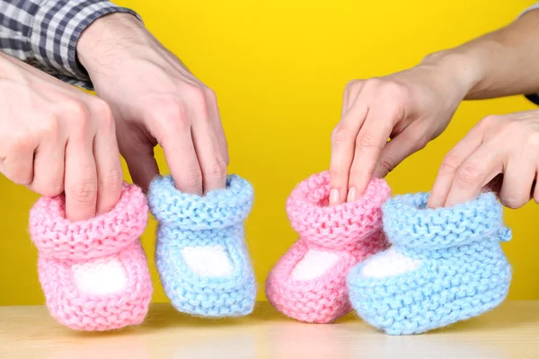 Ruce s háčkované botičky pro miminko, na barvu pozadí — Stock fotografie