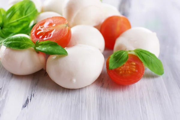 Välsmakande mozzarellaost med basilika och tomater, på träbord — Stockfoto