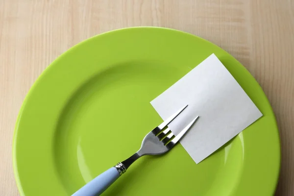 Lege nota papier gekoppeld aan vork, op de plaat, op een houten achtergrond kleur — Stockfoto