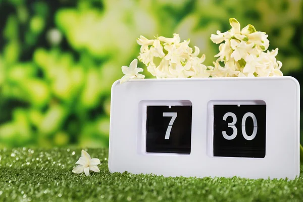 Digital alarm clock on green grass, on nature background — Stock Photo, Image