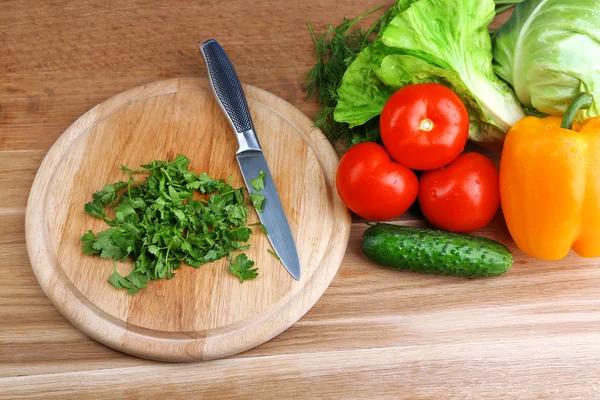 Composición con perejil picado sobre tabla de madera y verduras frescas, sobre fondo de madera —  Fotos de Stock