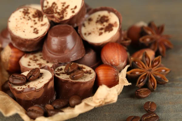 Doces de chocolate saborosos com grãos de café e nozes em fundo de madeira — Fotografia de Stock