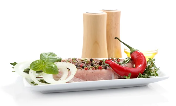 Стейк из сырого мяса со специями и травами на тарелке, изолированный на белом — стоковое фото
