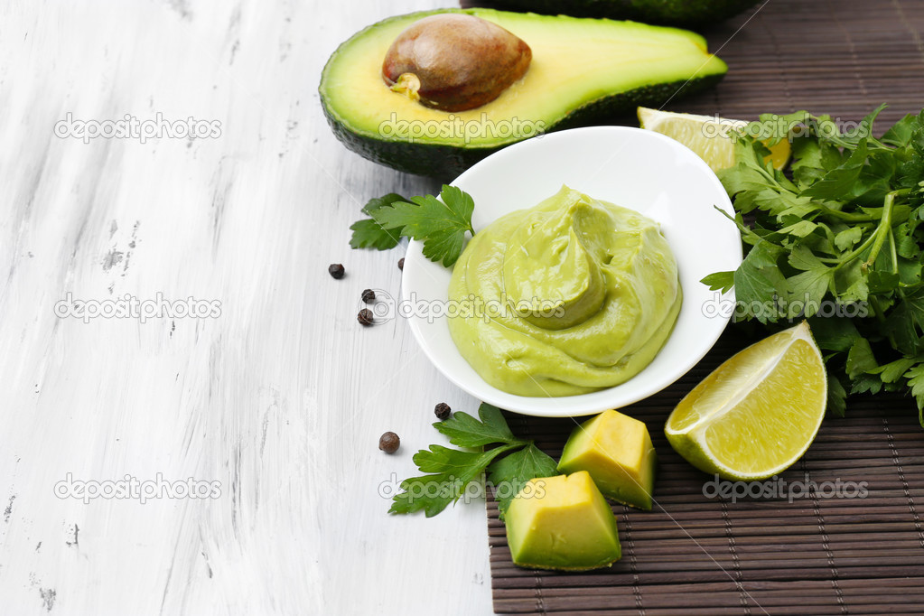 Fresh guacamole in bowl on wooden table