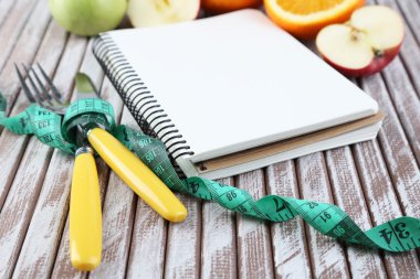 çatal bıçak takımı ile ölçme bant ve defter ahşap zemin üzerinde meyve ile bağlı