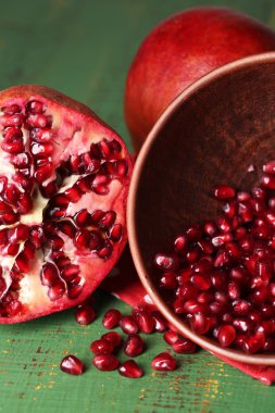 Olgun nar taneleri kase renkli ahşap zemin üzerinde