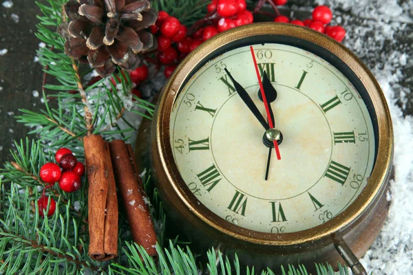 Clock with fir branches and berries on snow on wooden background — Stock Photo, Image