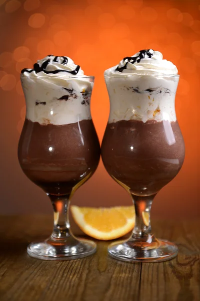 Lekker dessert met oranje, chocolade en crème saus, op houten tafel, op lichten achtergrond — Stockfoto