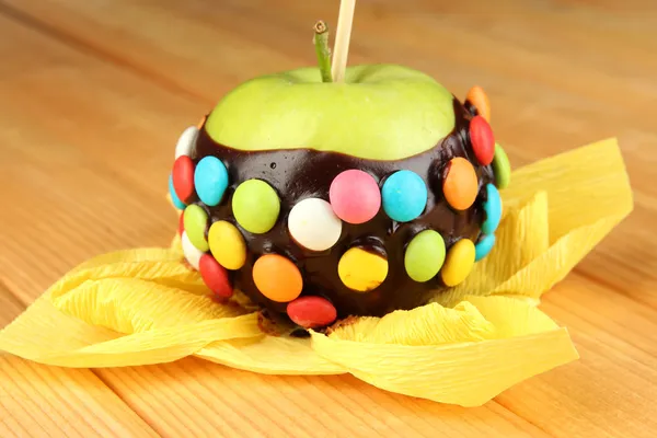 Candied apple on stick on wooden table — Stock Photo, Image