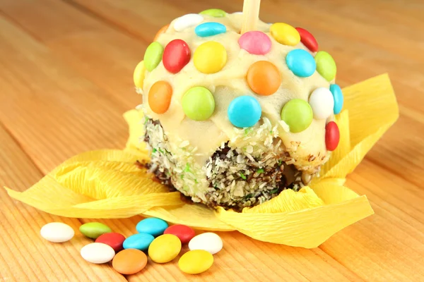 Candied apple on stick on wooden table — Stock Photo, Image