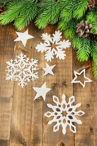 Beautiful paper snowflakes with fir branch on wooden background — Stock Photo, Image