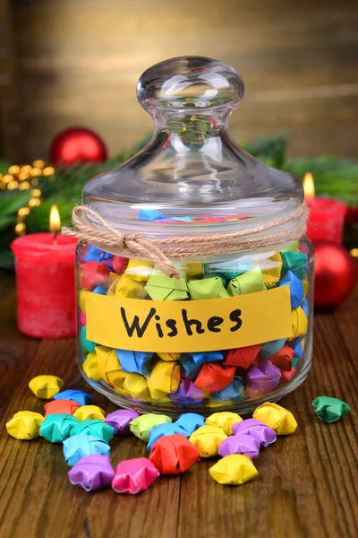 Paper stars with dreams in jar on table on wooden background